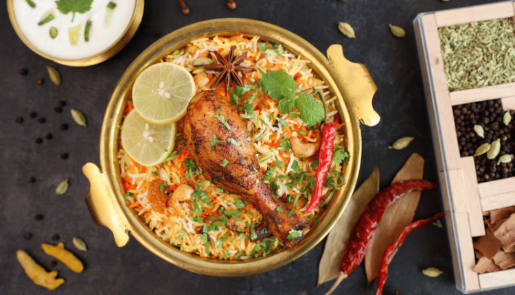 A tantalizing plate of Muradabadi Chicken Biryani garnished with fresh herbs and served with raita on the side.