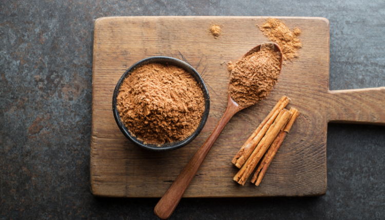 A close-up image of cinnamon sticks and ground cinnamon powder on a wooden surface, symbolizing the benefits and uses of cinnamon for health and wellness.