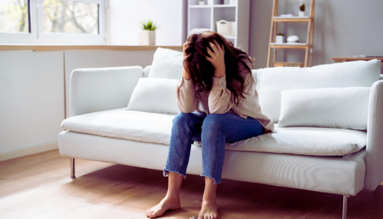 A person holding their head in distress, surrounded by icons representing obsessive thoughts and compulsive behaviors, illustrating the causes, types, and signs of OCD as discussed in the blog.