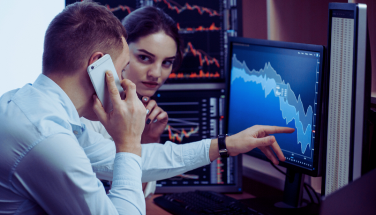 An image of a confident stockbroker working on multiple computer screens displaying stock market charts, graphs, and financial data. The broker is wearing a professional suit, with a focus on analyzing market trends. The background shows a bustling trading floor, emphasizing the fast-paced environment of the stock market. This image represents the blog's guide on How To Be A Stock Broker.